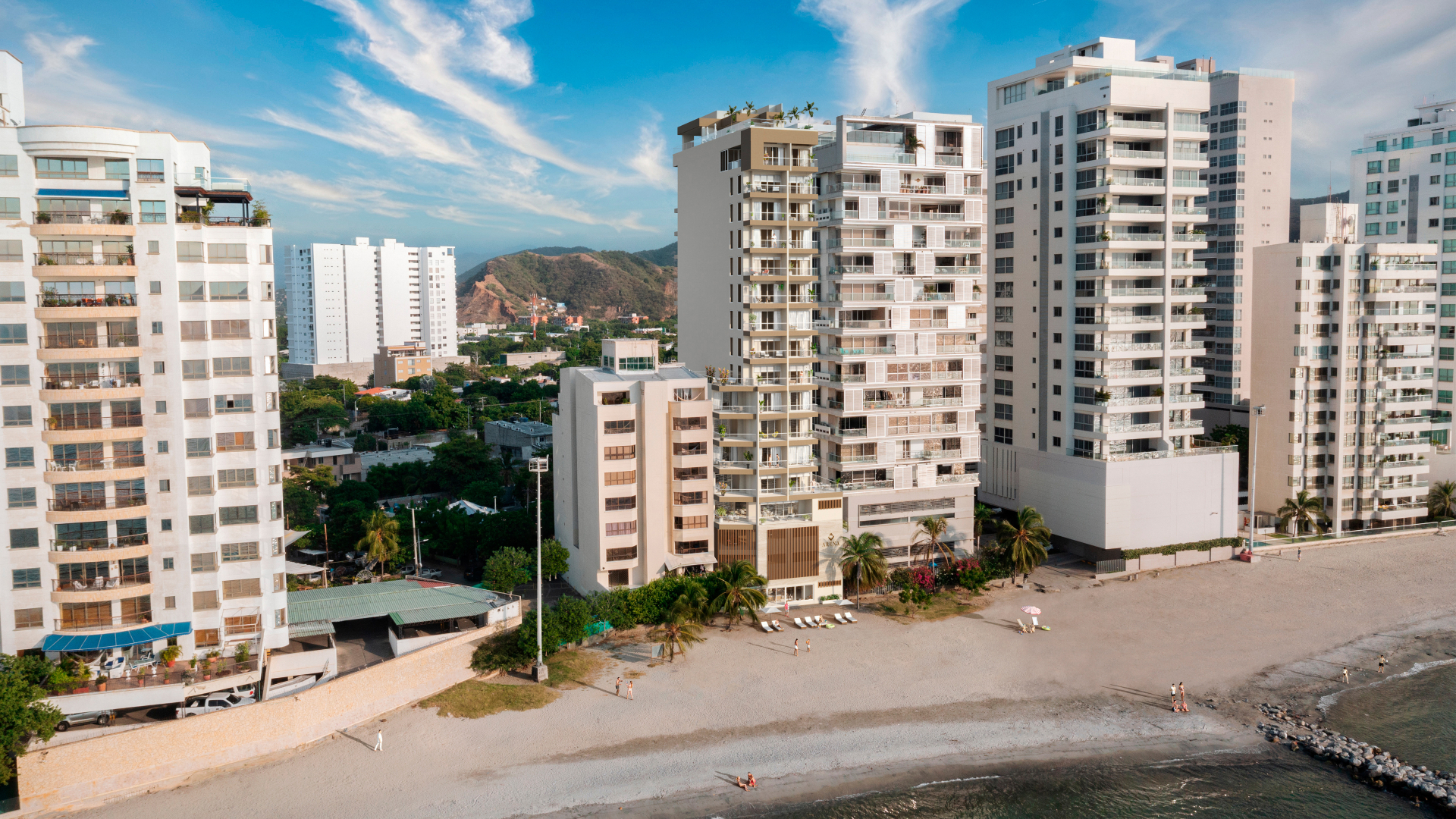 Fachada Arena Apartasuites frente al mar bajo cielo despejado
